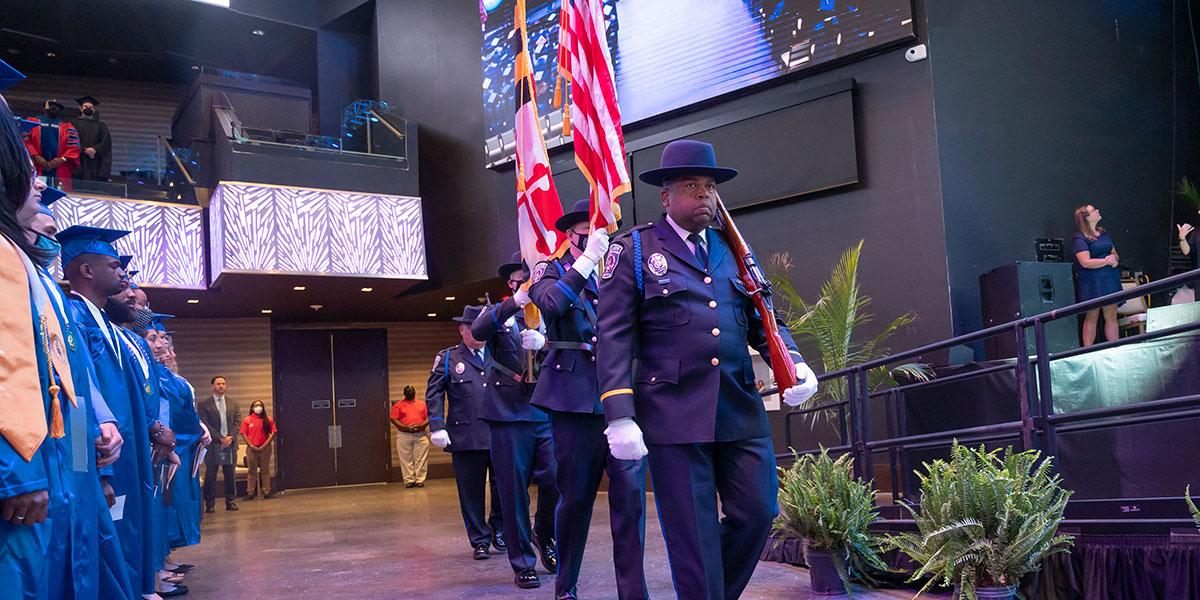 Department of Public Safety & Police officers in uniform and carrying flags at graduation